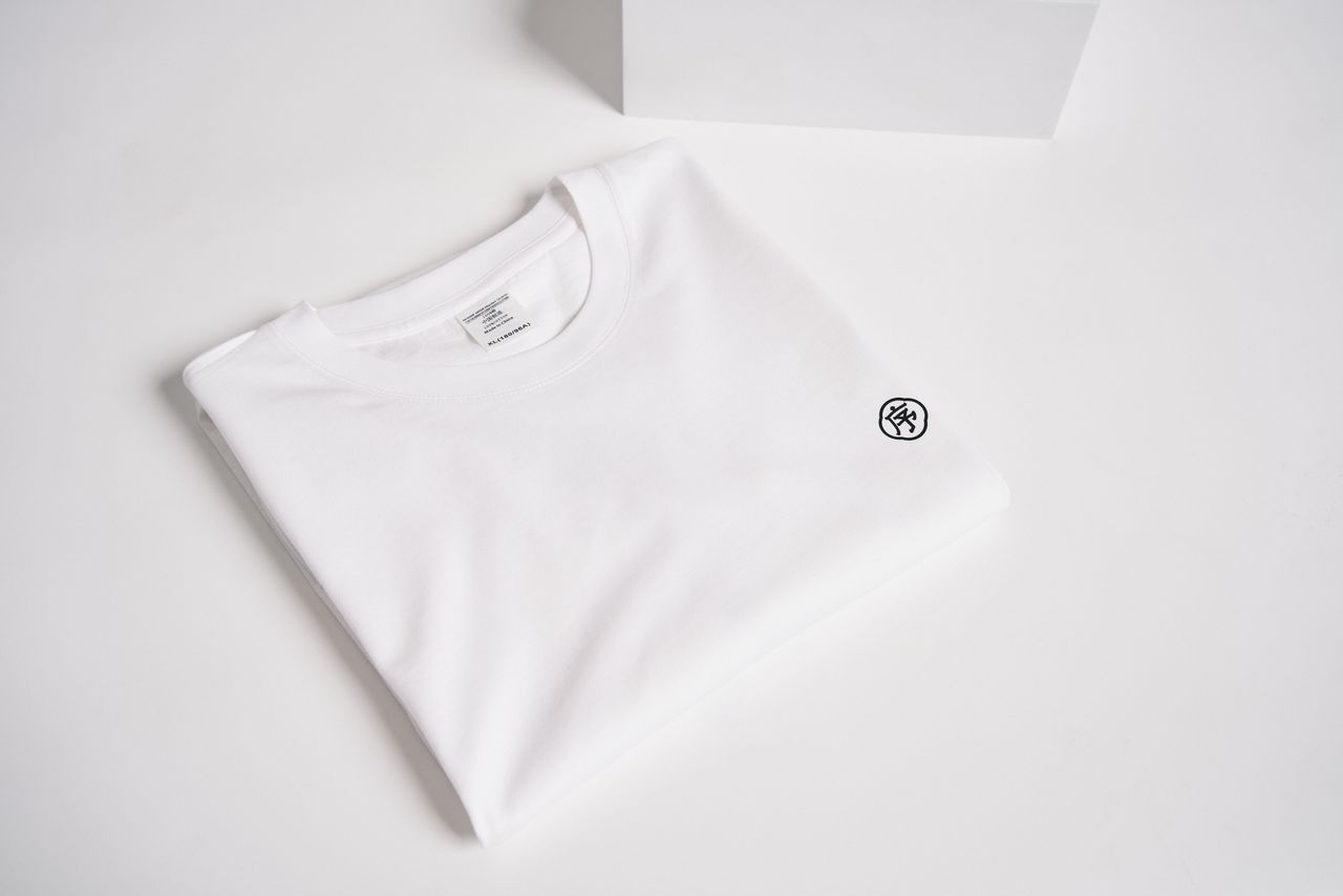 A minimalist folded white t-shirt on a white background showcasing simple and clean fashion style.