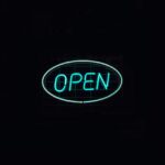 A vibrant neon 'Open' sign glows against a dark backdrop, ideal for business promotions.